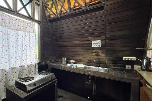 a kitchen with a sink and a stove at Urbanview Hotel AR Cottage Gambung in Gambung