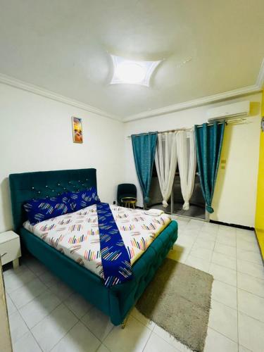 a bedroom with a bed in a room with blue curtains at Khurtis 225 in Abidjan