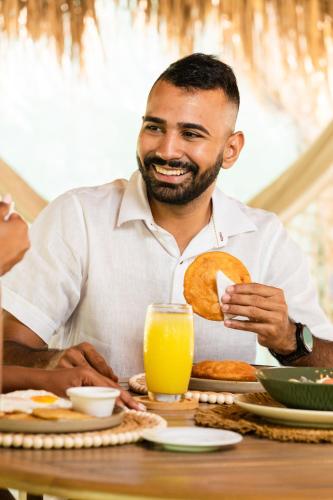 a man sitting at a table with a plate of food at Zirwa Hotel Boutique - Dentro del Parque Tayrona in El Zaino