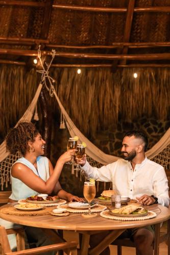 a man and woman sitting at a table with glasses of wine at Zirwa Hotel Boutique - Dentro del Parque Tayrona in El Zaino