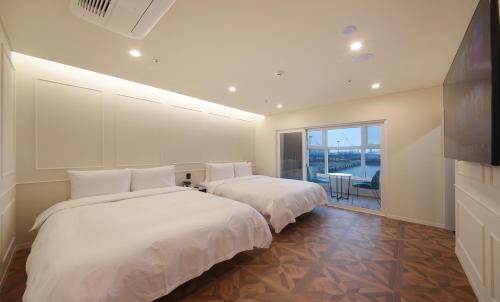 two beds in a large room with a balcony at Restia Incheon Bay Hotel in Incheon