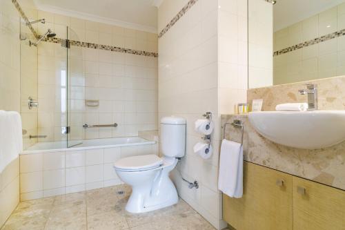 a bathroom with a toilet and a sink and a tub at Clarion Suites Gateway in Melbourne