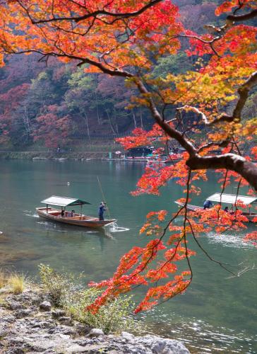 a man in a boat on a river with trees at Mulan Hostel in Kyoto