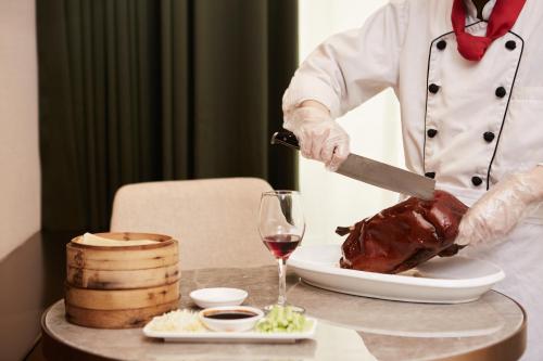 a chef cutting a turkey on a table with a glass of wine at THE YARD HOTEL BEIJING,BianyiFang - steps The Forbidden City - strolling through the imperial gardens is incredibly easy - The guest rooms blend modern comfort with Chinese charm - Peking duck - living in history Your Beijing adventure begins here in Beijing