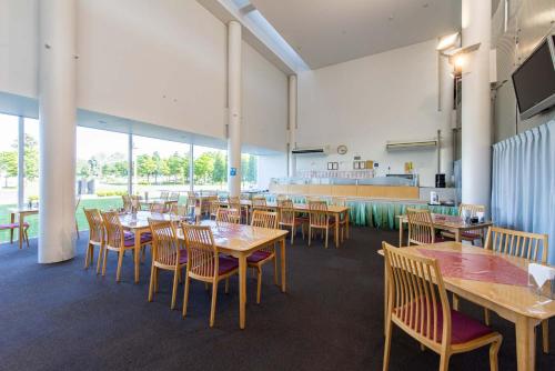a dining room with tables and chairs and windows at Sunhills Sarai in Shintotsukawa
