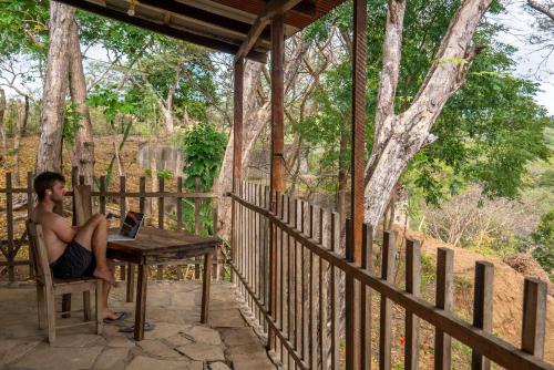 a man sitting at a table on a porch with a laptop at Casa Medusa in El Gigante
