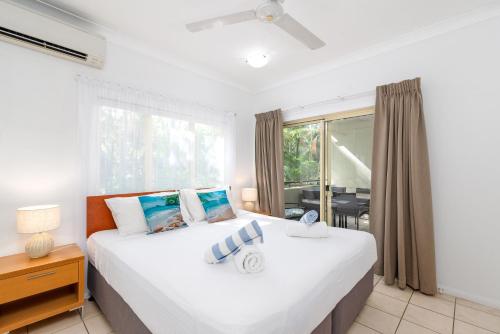 ein Schlafzimmer mit einem großen weißen Bett und einem Fenster in der Unterkunft Seascape Holidays at Plaza Resort in Port Douglas