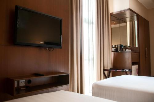 a hotel room with two beds and a flat screen tv at Swiss Hotel Apartment in Kuala Belait