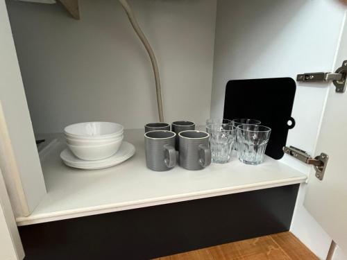 a shelf with cups and dishes on it at Neighbor's Hotel 五日市コイン通り in Hiroshima