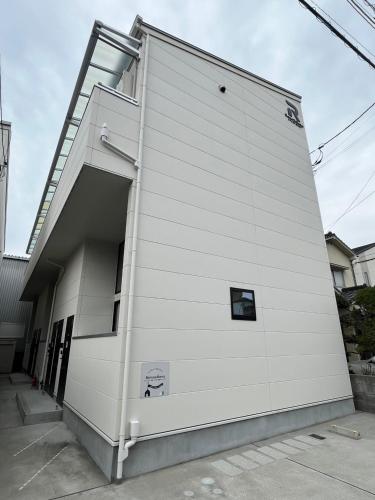 a white building with a large door on the side at Neighbor's Hotel 五日市コイン通り in Hiroshima