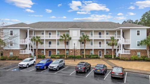 a large building with cars parked in a parking lot at Spacious 2BR Retreat with Pool Access - Barefoot in North Myrtle Beach