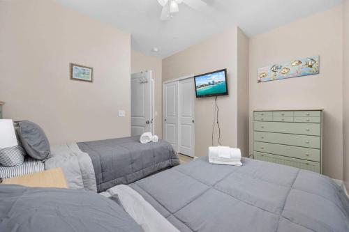 a bedroom with two beds and a tv on the wall at Spacious 2BR Retreat with Pool Access - Barefoot in North Myrtle Beach