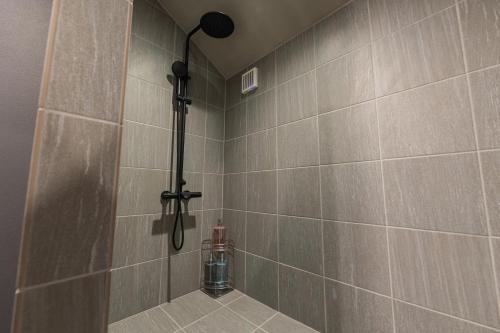 a shower in a bathroom with a tile wall at Tida Sesoko in Motobu