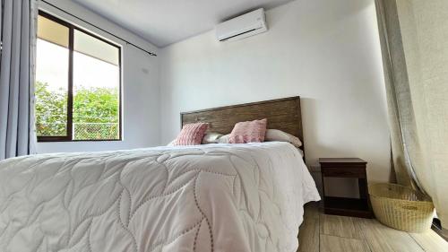 a white bedroom with a large bed with pink pillows at Quinta La Esperanza in Chachagua
