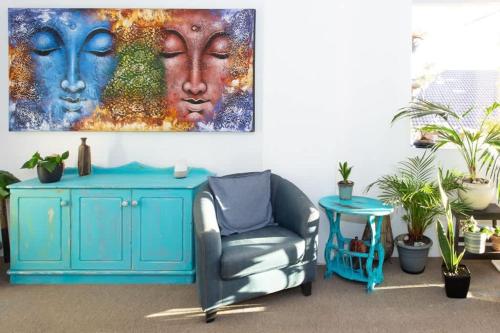 a living room with a blue chair and a painting at Beachside Oasis - Ocean Views and Walk to Everything in Wollongong