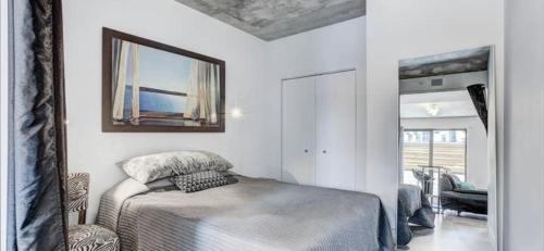 a white bedroom with a bed and a mirror at INCh in Montréal