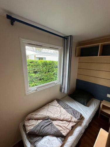 a small bedroom with a bed and a window at Mobil-home 5 personnes in Ouistreham