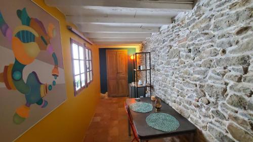 a living room with a stone wall and a table at La Concha 1 in Conques-sur-Orbiel
