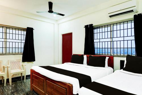 two beds in a room with two windows at Super Collection O Mahabalipuram in Mahabalipuram