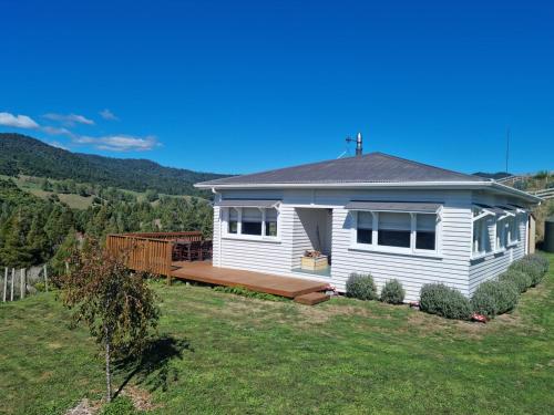 a white house with a deck in a yard at Waitawheta Cottage in Waihi