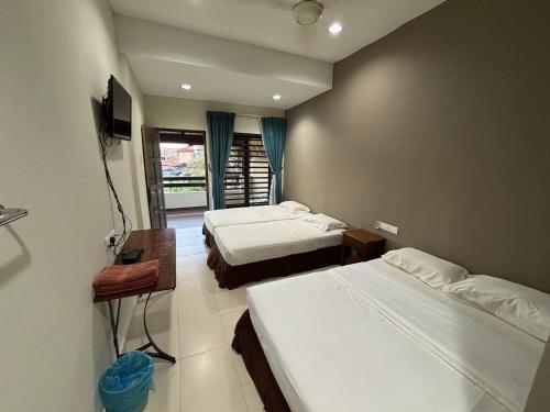 a hotel room with two beds and a television at Bamboo GuestHouse in Kuantan