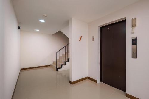 a hallway with a black door and stairs at Raspberry Mansion ราสเบอรี่ แมนชั่น in Samutprakarn