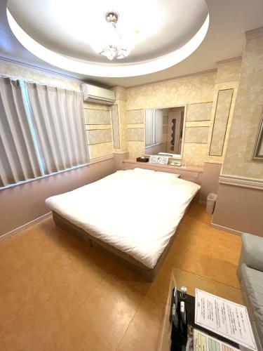 a bedroom with a large white bed and a ceiling at ホテルアンの家 in Ikaho
