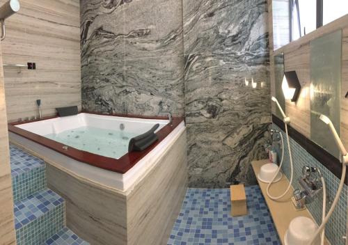 a bathroom with a tub with a stone wall at Hotel Yah Hanoi & Spa in Hanoi