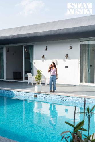 a woman taking a picture of a swimming pool at StayVista's Kundan Villa - Pet-Friendly Villa with Sprawling Lawn, Outdoor Pool in Jaipur