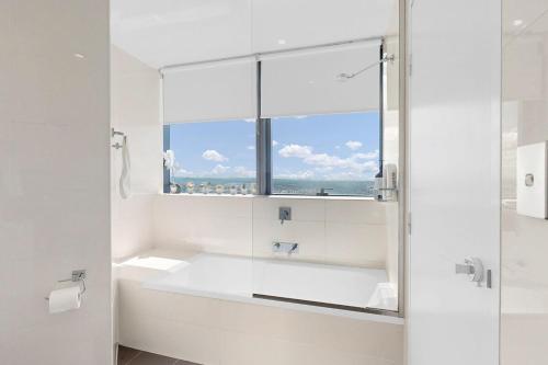 a white bathroom with a tub and a window at Cloud 56 Luxury Stay Level 56 with Free Onsite Parking in Brisbane