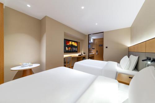a hotel room with two beds and a tv at Yibo Hotel - Pazhou Convention and Exhibition Center - Walking distance to Canton Fair in Guangzhou