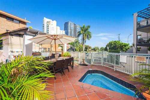 a patio with a table and an umbrella and a pool at Santa Fe by the Broadwater in Gold Coast