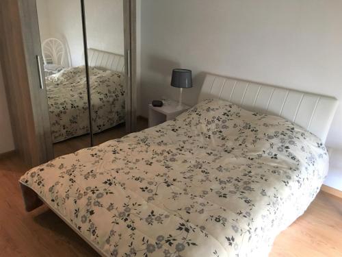 - une chambre avec un lit doté d'un couvre-lit floral et d'un miroir dans l'établissement Appartement moderne à 2 min de la plage, vue mer, animaux admis - FR-1-482-153, à Fort-Mahon-Plage