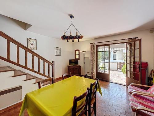 une salle à manger avec une table jaune et des escaliers dans l'établissement Maison calme pour 4 pers. proche centre, Saintes-Maries-de-la-Mer - FR-1-475-220, à Saintes-Maries-de-la-Mer