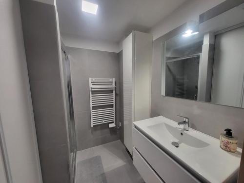 une salle de bain blanche avec un lavabo et un miroir dans l'établissement Appartement Montgenèvre avec terrasse, wifi et parking - FR-1-266-249, à Montgenèvre