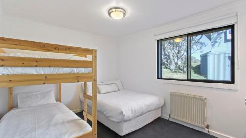 two bunk beds in a room with a window at Lawlers 30 in Mount Hotham