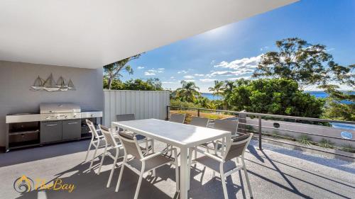 a dining room with a white table and chairs on a balcony at Water Views on Wallawa in Nelson Bay