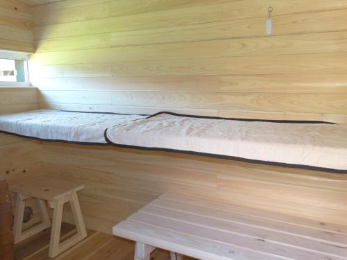 a bed in a wooden cabin with a wooden wall at 古民家ゲストハウスSatoyama in Kokuryō