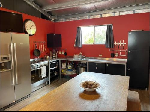 a kitchen with red walls and a table with a clock at Unique Australian Shed Style House in Dunsborough