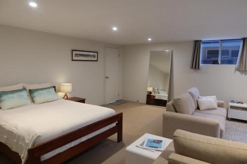 a bedroom with a bed and a living room with a couch at Unique Australian Shed Style House in Dunsborough
