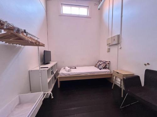 Una pequeña habitación con una cama y una ventana. en Rob Roy Room 5, en Adelaida