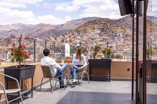 a man and a woman sitting at a table on a roof at Hotel Sky Mirador in Cusco