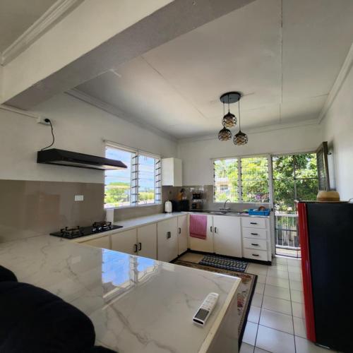 a kitchen with white cabinets and a large window at Wane's BnB in Nadi