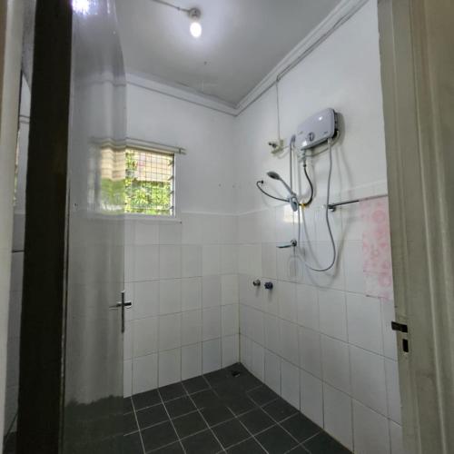 a bathroom with a shower with white tiles at Wane's BnB in Nadi