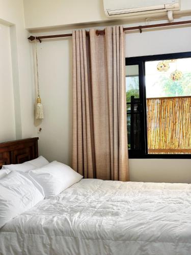 a bedroom with a white bed and a window at candy house ที่พักวัวลาย เชียงใหม่ in Chiang Mai