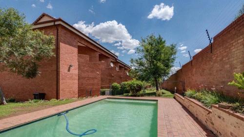 a swimming pool in front of a brick building at Savannah Lodge Apartments unit 81 in Roodepoort