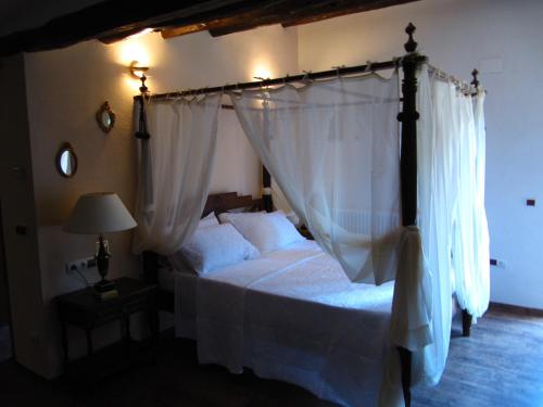 Schlafzimmer mit Himmelbett und weißen Vorhängen in der Unterkunft Ca l'Estruch in Vallclara