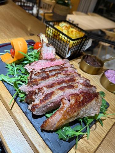 a piece of meat on a blue plate with salad at Na Vasi restavracija in prenočišča in Škofja Loka