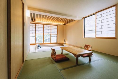 a room with a table and chairs and a window at Chikurakutei in Minami Aso