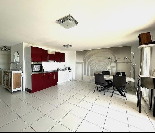une cuisine avec des armoires rouges et une table et des chaises dans l'établissement Sète vue mer, secteur des plages, T3 de standing climatisé avec grande terrasse, à Sète